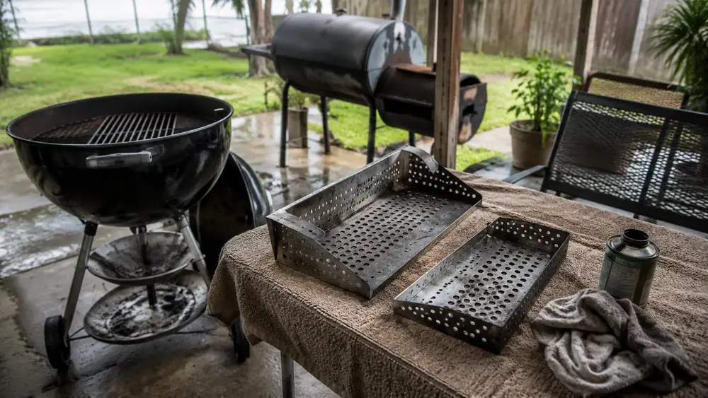 A disassembled Slow 'N Sear basket insert laid out on a towel on a patio table for cleaning and inspection
