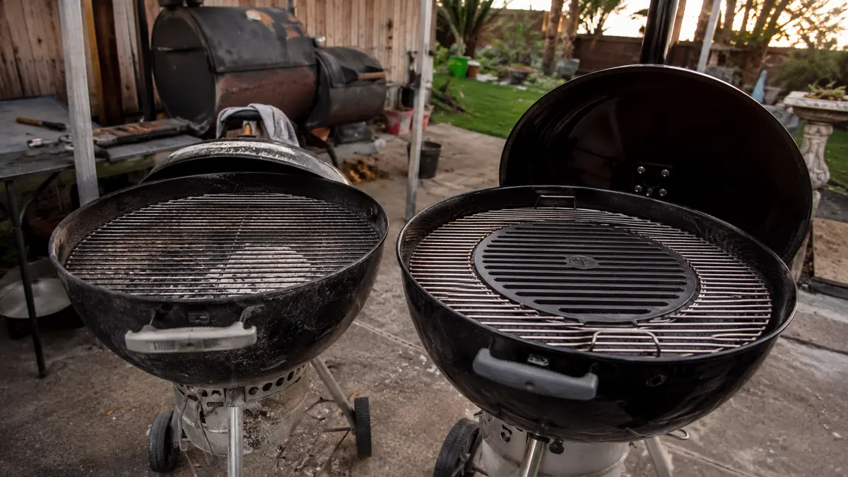An older kettle grill with a plain center-hub-less cooking grate next to a newer kettle grill fitted with the hinged Gourmet BBQ System grate